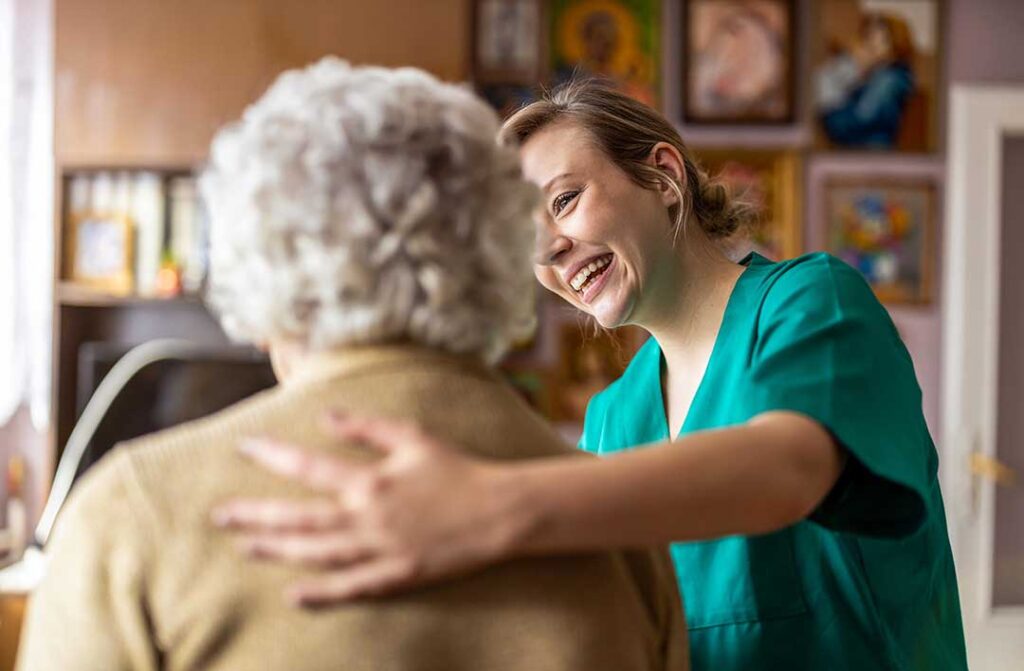 Older adult arranging family photos and a favorite lamp in a new assisted living room with a relative.