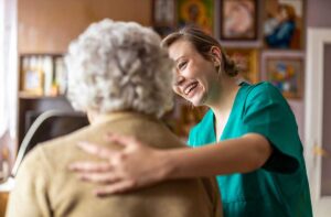 Older adult arranging family photos and a favorite lamp in a new assisted living room with a relative.