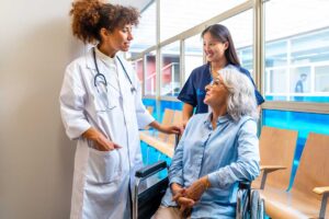 An older adult receives help from a caregiver in a comfortable assisted living room.